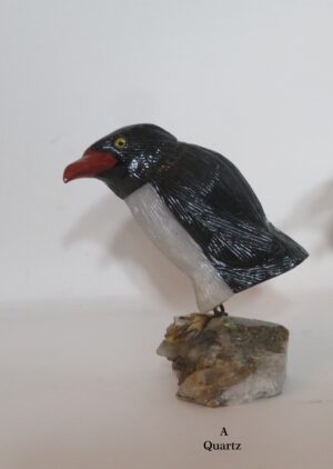 Quartz bird carving with red beak on rock